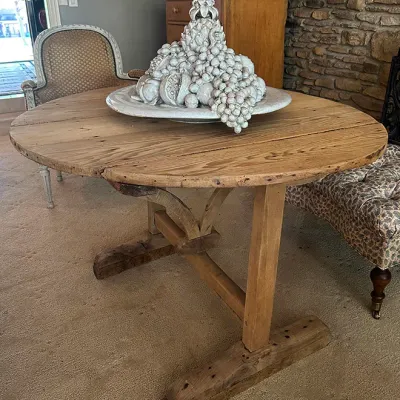 Sale Photo Thumbnail #145: Rustic rustic-style round wooden trestle table topped with a large glazed ceramic fruit motif centerpiece bowl.