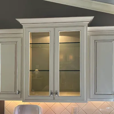 Sale Photo Thumbnail #41: Off-white traditional wall cabinet unit featuring crown molding, glass-front center doors with interior lighting, and silver hardware.