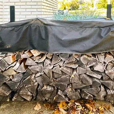 Sale Photo Thumbnail #224: Black metal outdoor firewood rack filled with split logs and fitted with a protective fabric top cover.