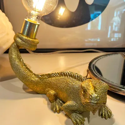 Sale Photo Thumbnail #104: Whimsical textured gold iguana table lamp featuring a bulb socket held at the tip of its curled tail.