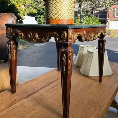Sale Photo Thumbnail #261: Ornate French Neoclassical style accent table featuring gilt carved details and a green marble top, displayed with a vintage ice bucket and lampshades.