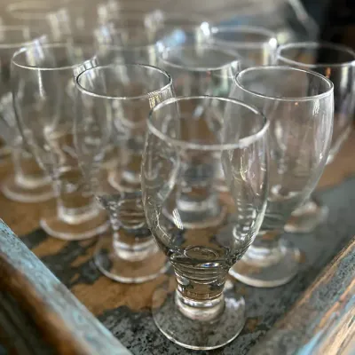 Sale Photo Thumbnail #136: Collection of clear stemmed glassware sitting in a rustic wooden tray.