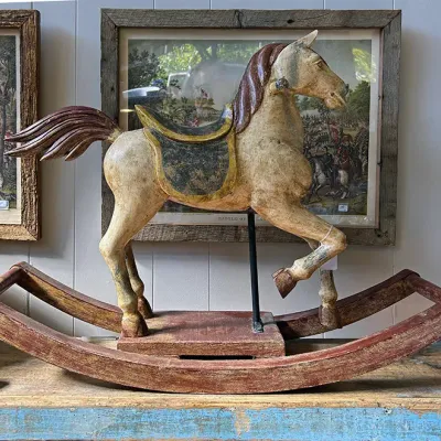 Sale Photo Thumbnail #297: Vintage carved wooden rocking horse with a distressed painted finish and red-painted rockers.