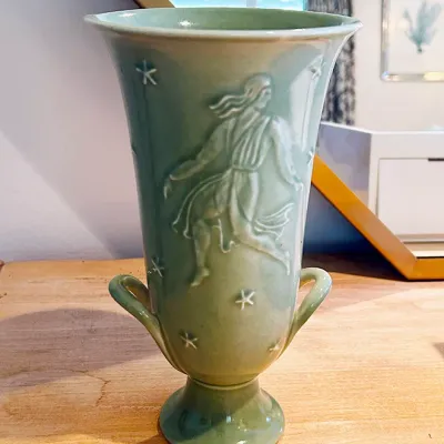 Sale Photo Thumbnail #199: Vintage mint green glazed ceramic vase featuring relief designs of a classical maiden and stars, complete with small side handles and a pedestal base.