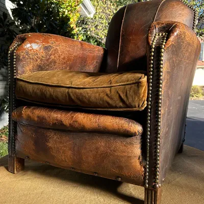 Sale Photo Thumbnail #259: Vintage French Art Deco style leather club chair featuring heavy brass nailhead trim and a distressed, patinated brown leather finish.