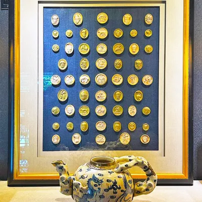 Sale Photo Thumbnail #4: Framed collection of Grand Tour style plaster cameo intaglios displayed above a blue and white ceramic teapot with a dragon-shaped handle and spout.