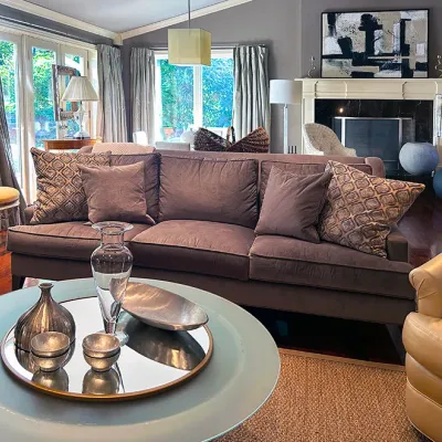 Sale Photo Thumbnail #35: Contemporary living room setup featuring a taupe velvet three-seat sofa with patterned throw pillows, a round glass-top coffee table with decorative silver accent pieces, and a tan leather armchair.