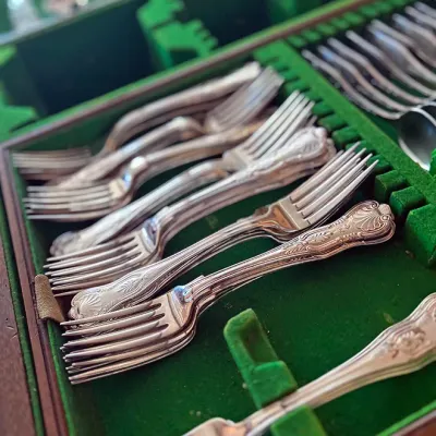 Sale Photo Thumbnail #130: Vintage sterling silver flatware set with elaborate shell motif handles, organized inside a green felt-lined storage chest.