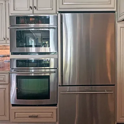 Sale Photo Thumbnail #51: Modern stainless steel kitchen appliances, including a double wall oven unit and a bottom-freezer refrigerator, built into off-white glazed cabinetry.