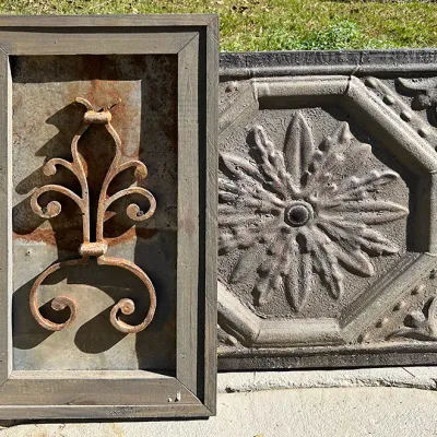 Sale Photo Thumbnail #250: Rustic wall decor pieces including a framed scrolled wrought iron motif on weathered metal and a textured embossed floral tin tile.