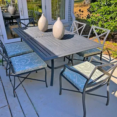 Sale Photo Thumbnail #240: Outdoor patio dining set featuring a dark metal slatted table and six matching chairs with light blue patterned seat cushions.