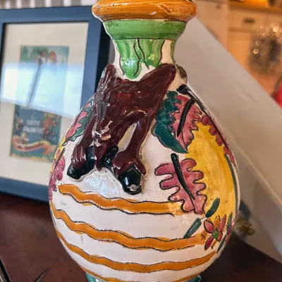 Sale Photo Thumbnail #288: Hand-painted ceramic lamp base featuring relief details of a bat-like creature and floral patterns, showing some paint wear on the raised surfaces.