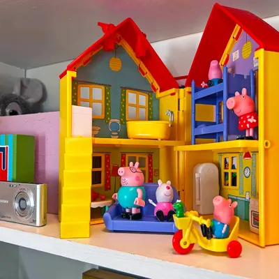 Sale Photo Thumbnail #30: Peppa Pig fold-out dollhouse playset with character figures and furniture, displayed alongside a silver Sony Cyber-shot compact digital camera.