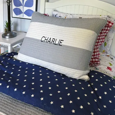 Sale Photo Thumbnail #212: Twin bed setup featuring a white beadboard headboard, striped quilt bedding, a star-patterned duvet, and a personalized 'Charlie' pillow sham.