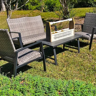 Sale Photo Thumbnail #243: Four-piece outdoor patio set featuring a love seat, two armchairs, and a low coffee table, all constructed with dark metal frames and grey resin wicker weave.