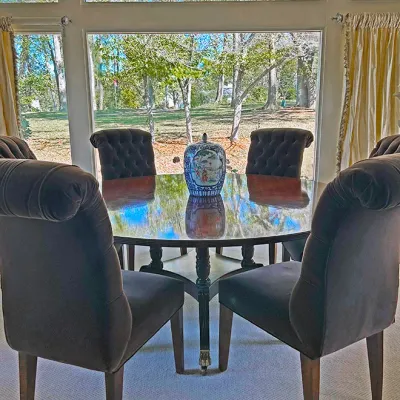 Sale Photo Thumbnail #143: Polished round wooden dining table paired with dark velvet tufted dining chairs, centered with a decorative Chinese porcelain ginger jar.