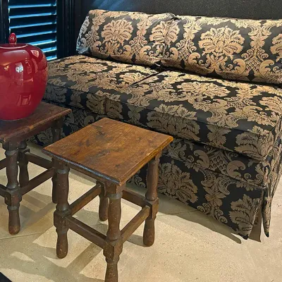 Sale Photo Thumbnail #15: Traditional armless loveseat featuring a black and gold damask pattern fabric, paired with two rustic wooden side stools and a glossy red ceramic urn.