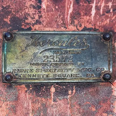 Sale Photo Thumbnail #74: Vintage brass manufacturer's plate for Hercules by Fibre Specialty Mfg. Co. attached to a textured, weathered surface with rivets.