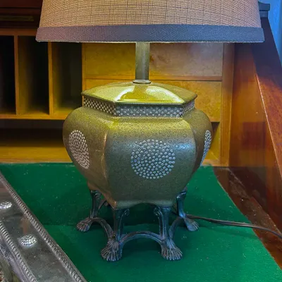 Sale Photo Thumbnail #150: Mid-century ceramic ginger jar table lamp with a olive green crackle glaze, beaded silver-tone details, cast metal claw feet, and a woven shade.
