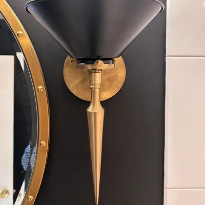 Sale Photo Thumbnail #172: Mid-century modern wall sconce featuring a matte black cone-shaped shade and a brass finish pointed-torch base.