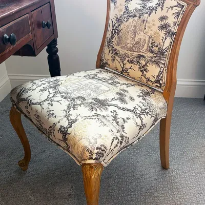 Sale Photo Thumbnail #211: French Provincial style side chair featuring a carved wooden frame and black and cream toile de Jouy upholstery.