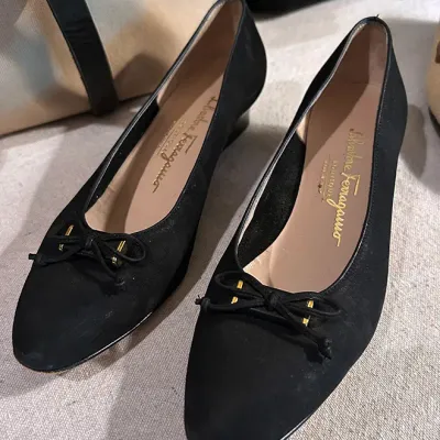 Sale Photo Thumbnail #157: Pair of Salvatore Ferragamo black suede low-wedge pumps featuring a front bow with gold-tone hardware detail.