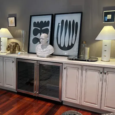Sale Photo Thumbnail #64: Long custom cream credenza featuring an integrated dual-zone stainless steel wine fridge, decorative lamps, framed abstract art prints, and home decor items.