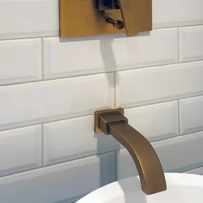 Sale Photo Thumbnail #174: Modern wall-mounted brass sink faucet and matching single-lever control valve set against white subway tile.