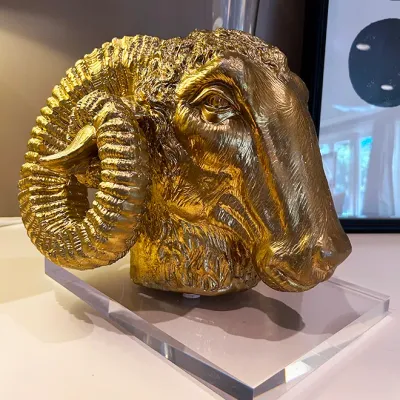 Sale Photo Thumbnail #66: Hollywood Regency style gilded ram's head bust sculpture mounted on a clear acrylic plinth base.