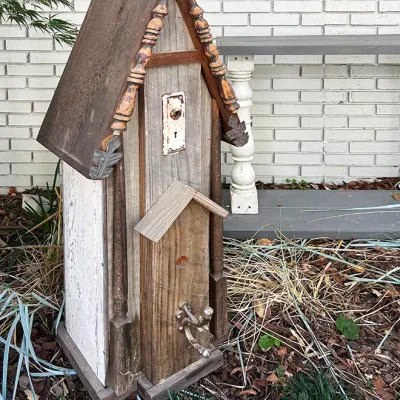 Sale Photo Thumbnail #239: Rustic handcrafted wooden birdhouse featuring repurposed materials, including a vintage keyhole escutcheon plate and ornate metal faucet handle perch.