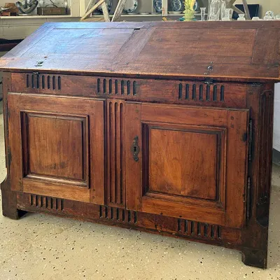 Sale Photo Thumbnail #269: Antique wooden slanted clerk's desk featuring slotted ventilation details, paneled cabinet doors, and original hardware.