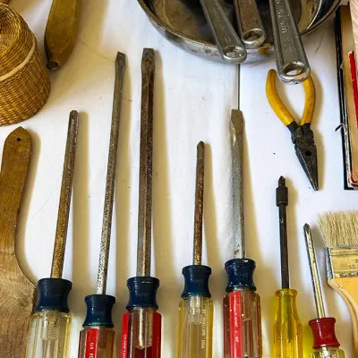 Sale Photo Thumbnail #283: Collection of vintage hand tools including Craftsman screwdrivers, adjustable wrenches in a metal dish, and needle-nose pliers.