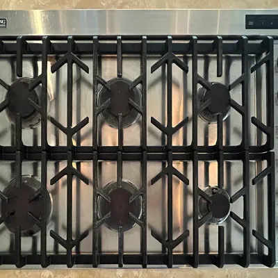 Sale Photo Thumbnail #49: Viking Professional six-burner stainless steel gas cooktop with heavy-duty cast iron grates and side control knobs.