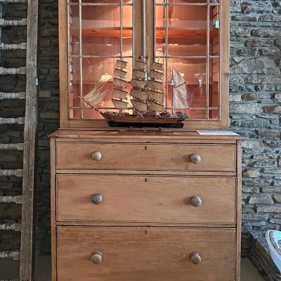 Sale Photo Thumbnail #3: Antique pine two-piece hutch featuring glazed upper doors with geometric mullions and a lower chest of three wide drawers with wooden knobs.