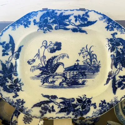 Sale Photo Thumbnail #256: Antique blue and white flow blue transferware platter with a floral and Asian-inspired pavilion motif, displaying visible crazing throughout.