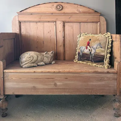 Sale Photo Thumbnail #119: Antique rustic pine bench featuring turned legs, a high paneled backrest, a carved cat figure, and an equestrian tapestry accent pillow.