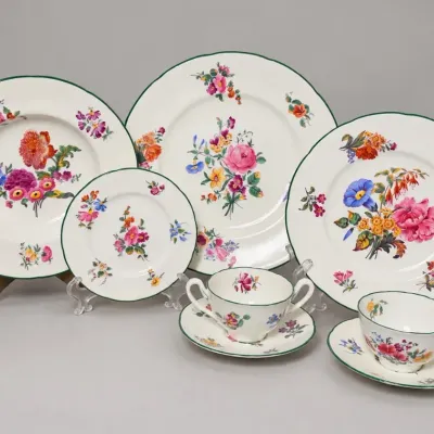 Sale Photo Thumbnail #74: Vintage botanical porcelain dishware set featuring hand-painted floral bouquets, scalloped edges, and green rim trim, including plates, saucers, and teacups.