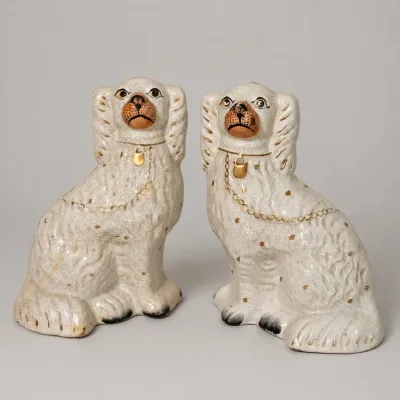 Sale Photo Thumbnail #33: Pair of antique Staffordshire ceramic spaniel figurines with hand-painted gold locket accents and crazed white glaze.