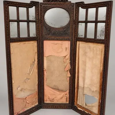 Sale Photo Thumbnail #98: Antique three-panel carved wooden dressing screen with mirrored upper sections and ribbon-and-bow cresting, featuring heavily distressed pink fabric lower panels in need of restoration.