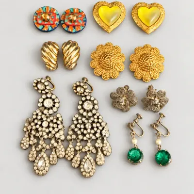 Sale Photo Thumbnail #51: Collection of vintage clip-on and screw-back earrings, including large rhinestone chandelier dangles, gold-tone florals, heart shapes, and filigree designs.