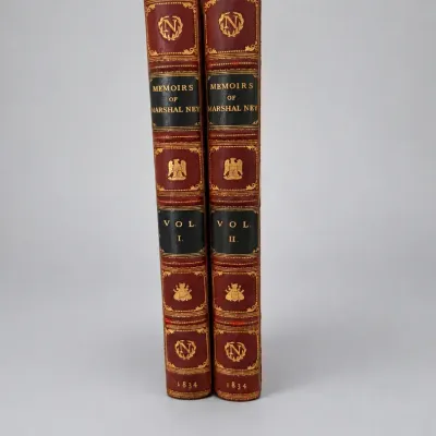 Sale Photo Thumbnail #85: Two-volume leather-bound set of 'Memoirs of Marshal Ney,' published in 1834. Features rich red leather spines decorated with gilt tooling, Napoleonic motifs, and black leather title labels.