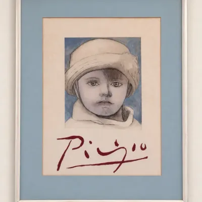 Sale Photo Thumbnail #72: Framed Pablo Picasso exhibition print featuring a portrait of a child, set under a blue mat in a silver metal frame.