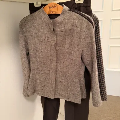 Sale Photo Thumbnail #75: Women's two-piece ensemble featuring a textured grey mandarin-collar jacket and dark dress trousers displayed on a hanger.