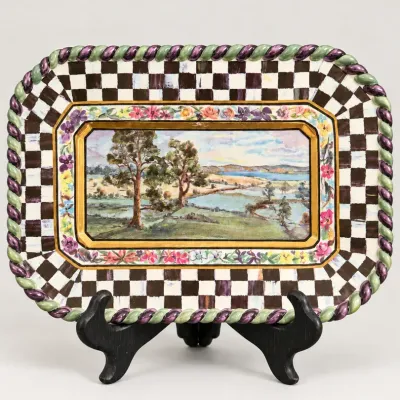 Sale Photo Thumbnail #48: Hand-painted MacKenzie-Childs ceramic tray featuring a central landscape scene bordered by floral motifs, a black and white Courtly Check pattern, and a twisted purple and green rope edge.