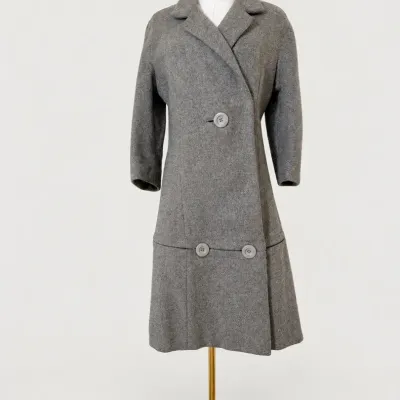Sale Photo Thumbnail #63: Vintage mid-century grey wool overcoat displayed on a mannequin, featuring large decorative buttons and a notched collar.