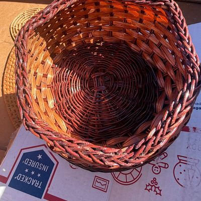 Sale Photo Thumbnail #284: Handwoven reddish-brown wicker basket featuring a braided rim and spiral base construction.