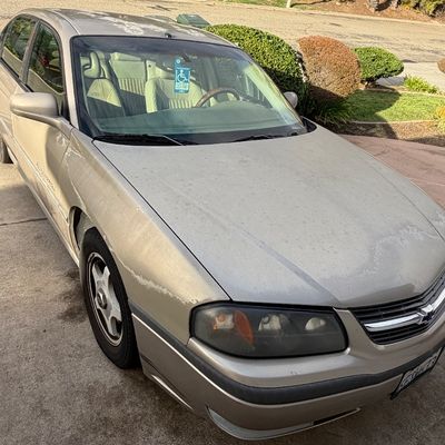 Sale Photo Thumbnail #3: Early 2000s Chevrolet Impala sedan in gold paint, showing notable clear coat peeling and sun wear on the hood and roof.