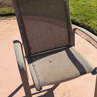 Sale Photo Thumbnail #64: Contemporary metal outdoor armchair with a brown mesh sling seat and backrest, showing some scuffs and wear on the frame.