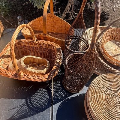 Sale Photo Thumbnail #288: Collection of assorted woven baskets and wine holders displayed outdoors, featuring various natural wicker, cane, and reed designs.