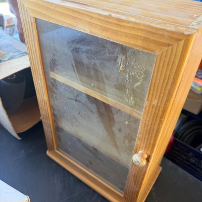 Sale Photo Thumbnail #237: Small rustic wooden display cabinet featuring a glass door with a round wooden knob and interior shelving.